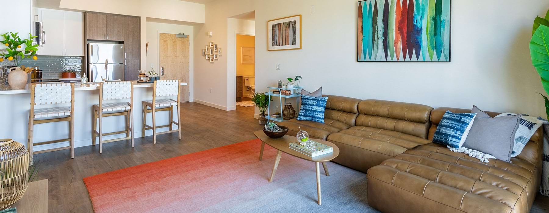 Spacious and well lit living room with wood floors and an open floor plan with access to the kitchen.