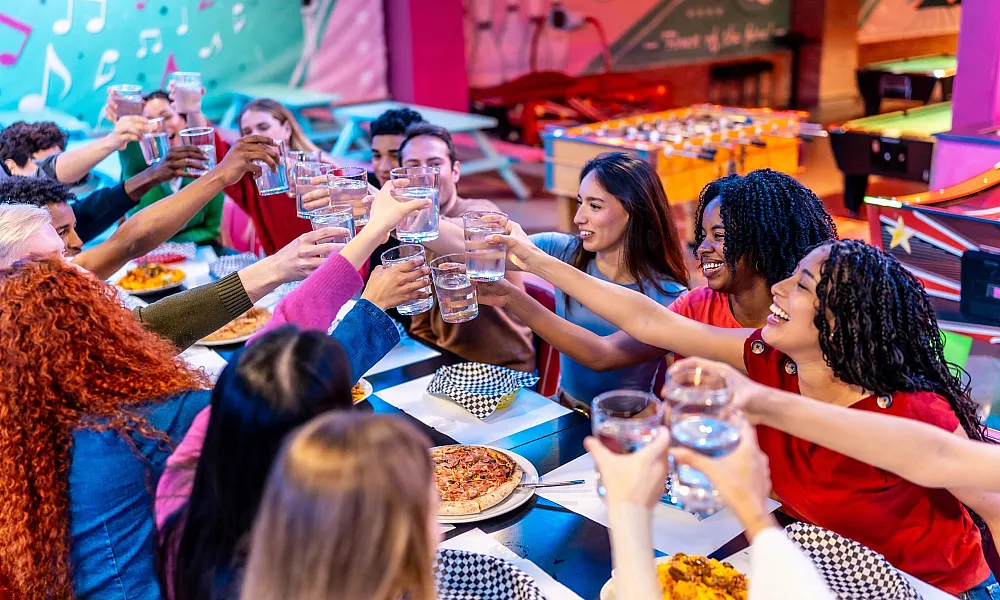 group of friends toasting with water eating together