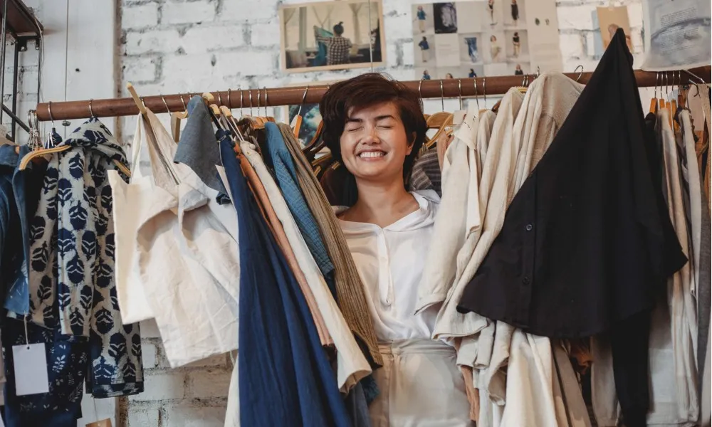 woman peeking through clothing rack in store