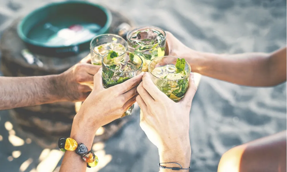 hands with drinks in hand on beach