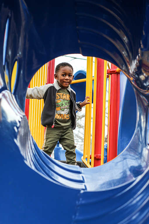 A child in a black shirt with the word "STAR" on it is standing in a blue tunnel.
