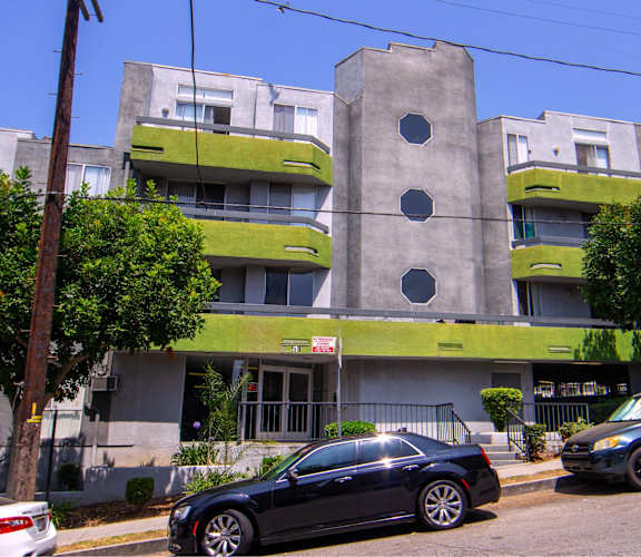 A black car is parked in front of a grey and green building.