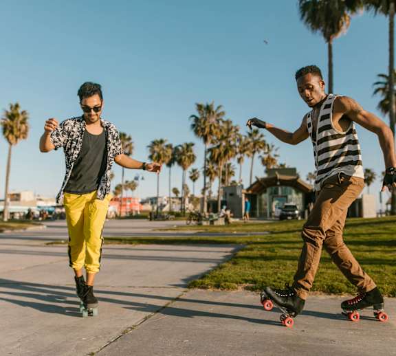 Two men are skateboarding in a park.