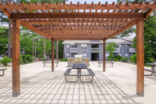 a picnic area with a table and benches under a wooden pergola
