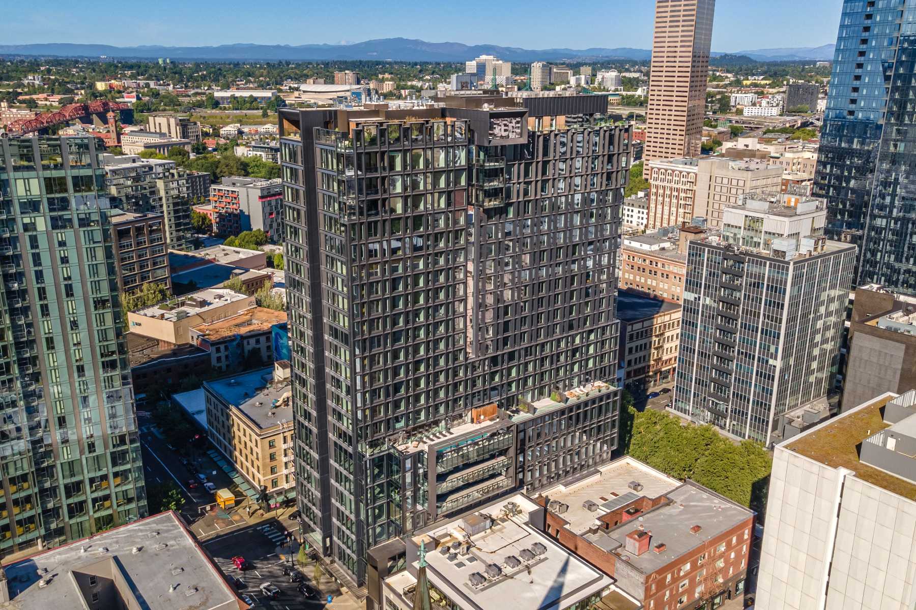 Apartments for Rent in Downtown Portland, OR - The Residences at 11W - Aerial View of Property Exterior with Glass Windows, Surrounding Urban Environment, and Nearby Greenery.