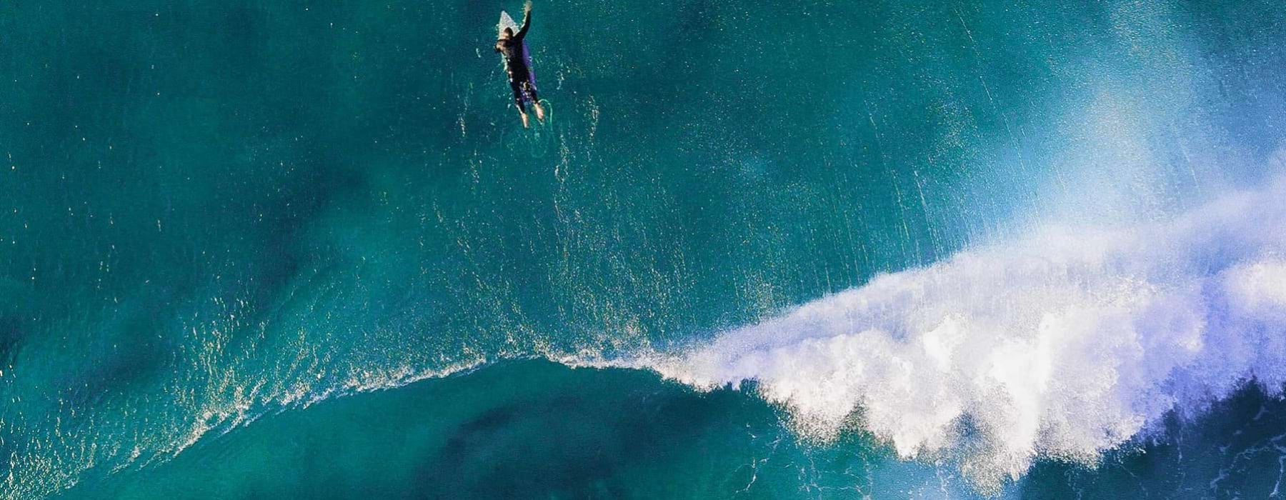 A person on a surfboard in the ocean near Lucia at Aviara apartments for rent in Carlsbad, CA.