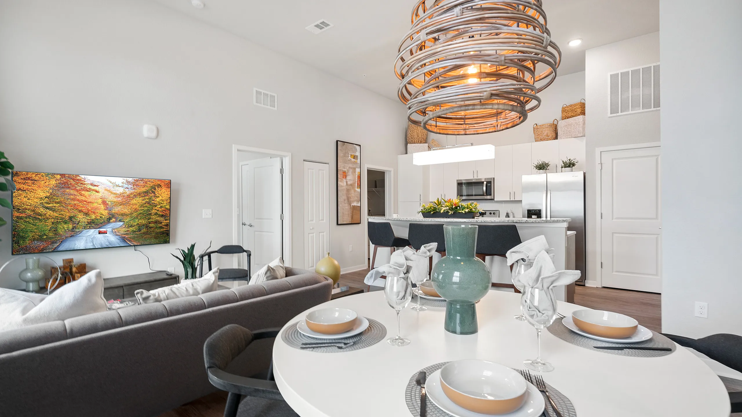 Modern open-concept living space with elegant dining area, stylish kitchen, and cozy lounge featuring a large screen TV.