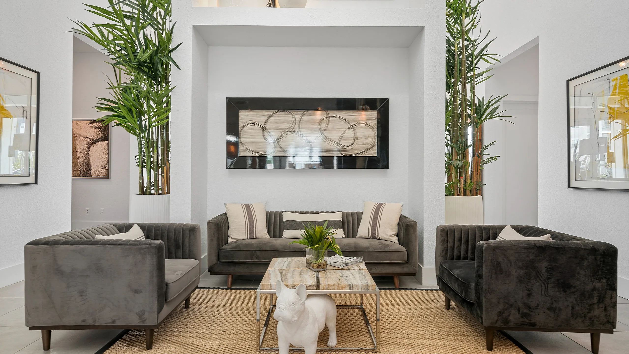 Luxurious modern living room with elegant grey sofas, stylish decor, and lush green plants creating a serene atmosphere.