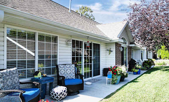 A patio with a table and chairs is outside a house.
