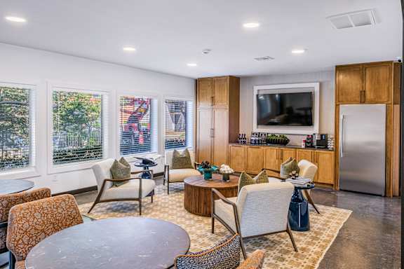 A modern living room with a television, a kitchen area, and a dining table at Water Ridge Apartments , Irving, 75061