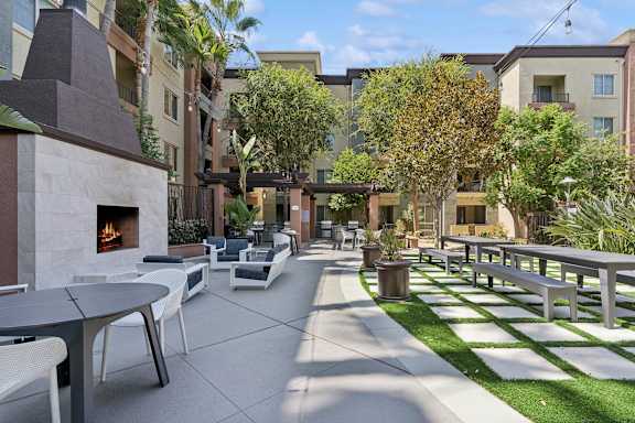 A patio with a fireplace and chairs. at The Kitt at Warner Center Apartments, California, 91303