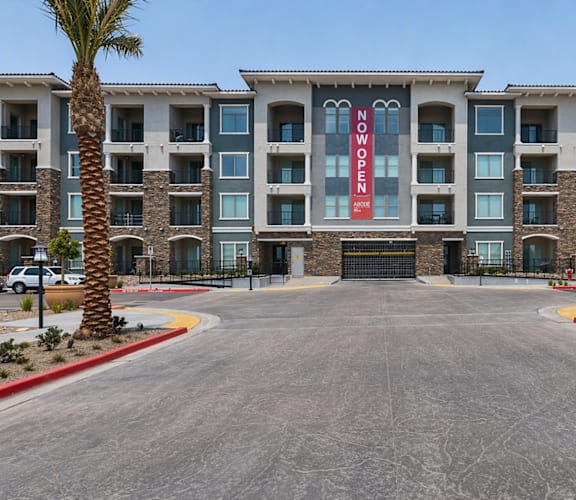 A large building with a red sign that says "NOW OPEN" is surrounded by palm trees.