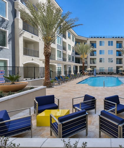 A pool surrounded by blue chairs and palm trees.