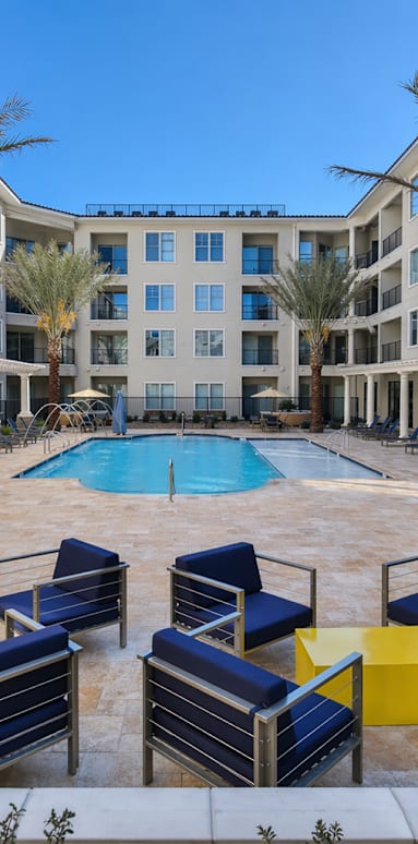 A pool surrounded by blue chairs and palm trees.