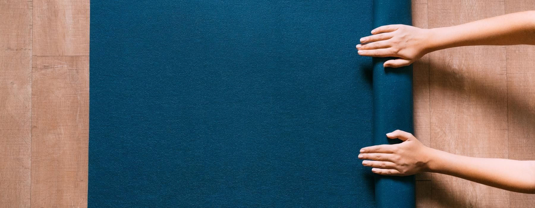 a person rolling a blue yoga mat