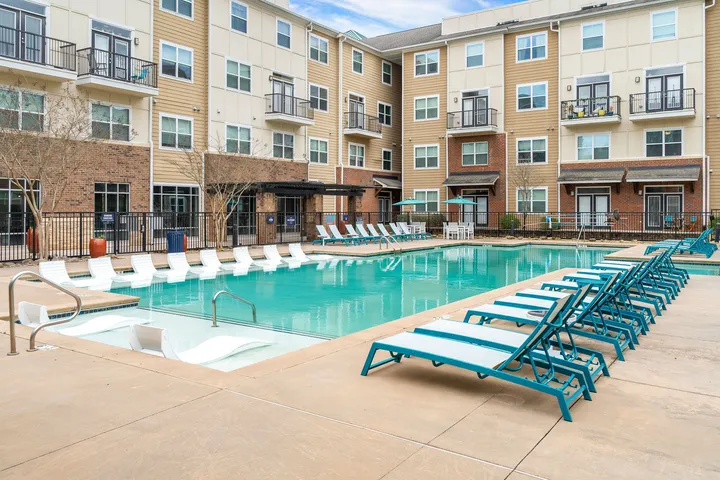 Elegant apartment complex with a stunning outdoor pool area, surrounded by modern architecture and inviting lounge chairs for relaxation.