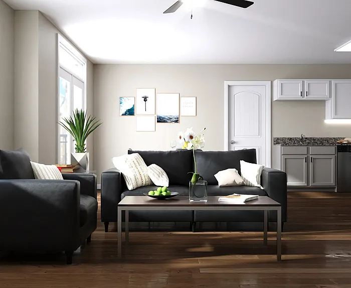 Modern open-concept living room with sleek black sofas, elegant decor, and a bright, spacious kitchen in the background.