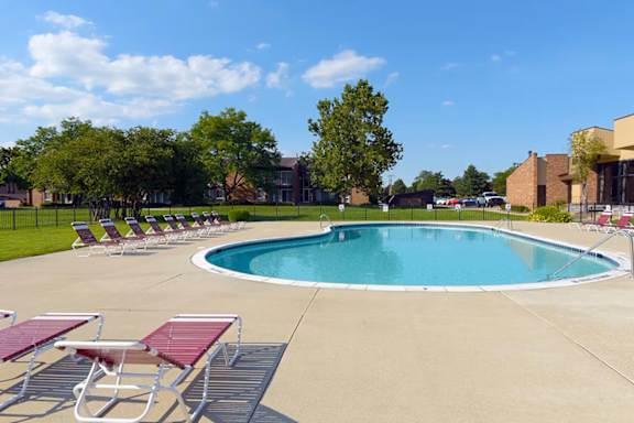 A swimming pool surrounded by red lounge chairs.