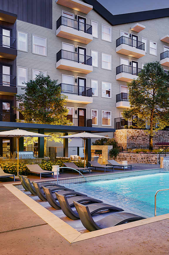 an outdoor swimming pool with lounge chairs in front of an apartment building