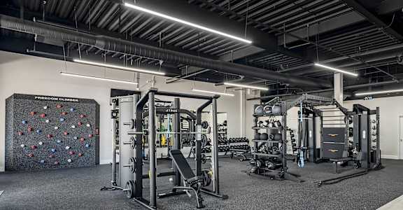 a gym with weights machines and a large rock wall at Villaggio Apartments, Louisiana