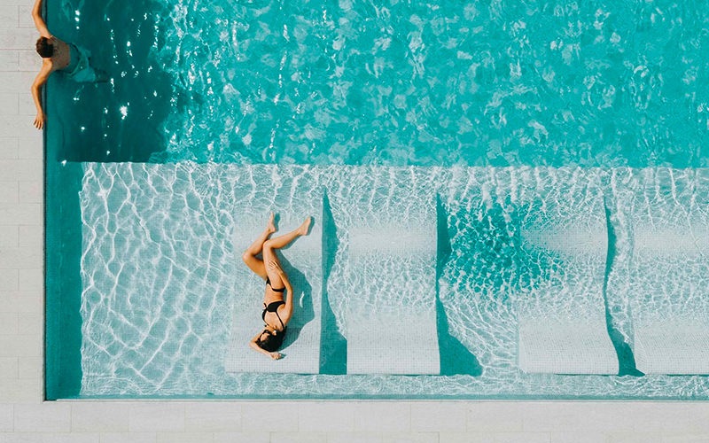 an aerial view of a pool with two people relaxing
