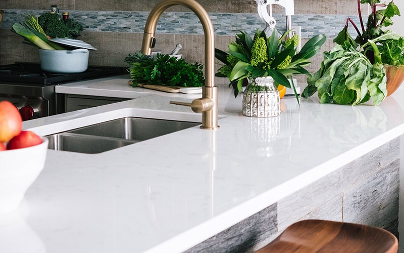 a white counter with many plants and veggies on it