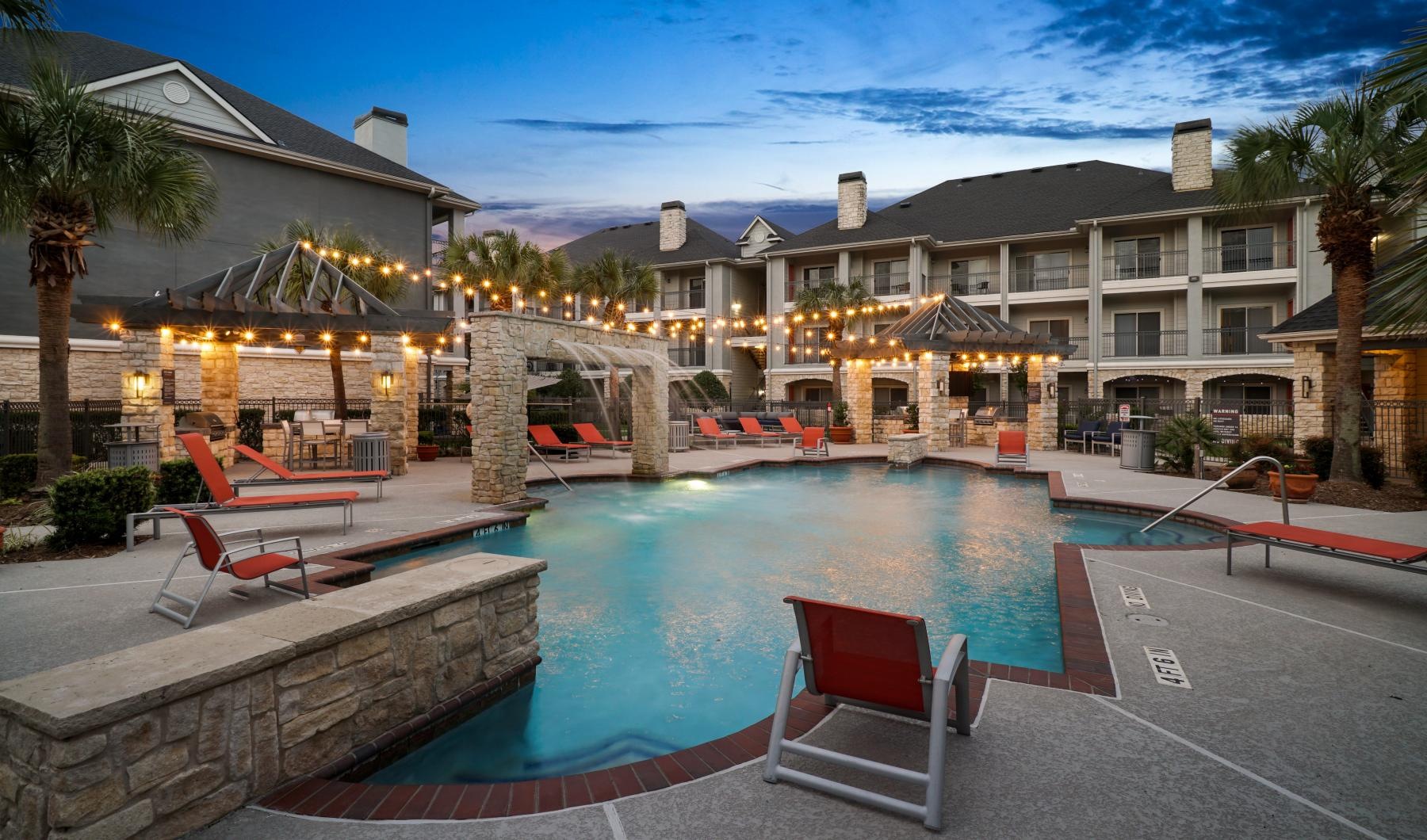 a swimming pool with chairs and umbrellas next to a building