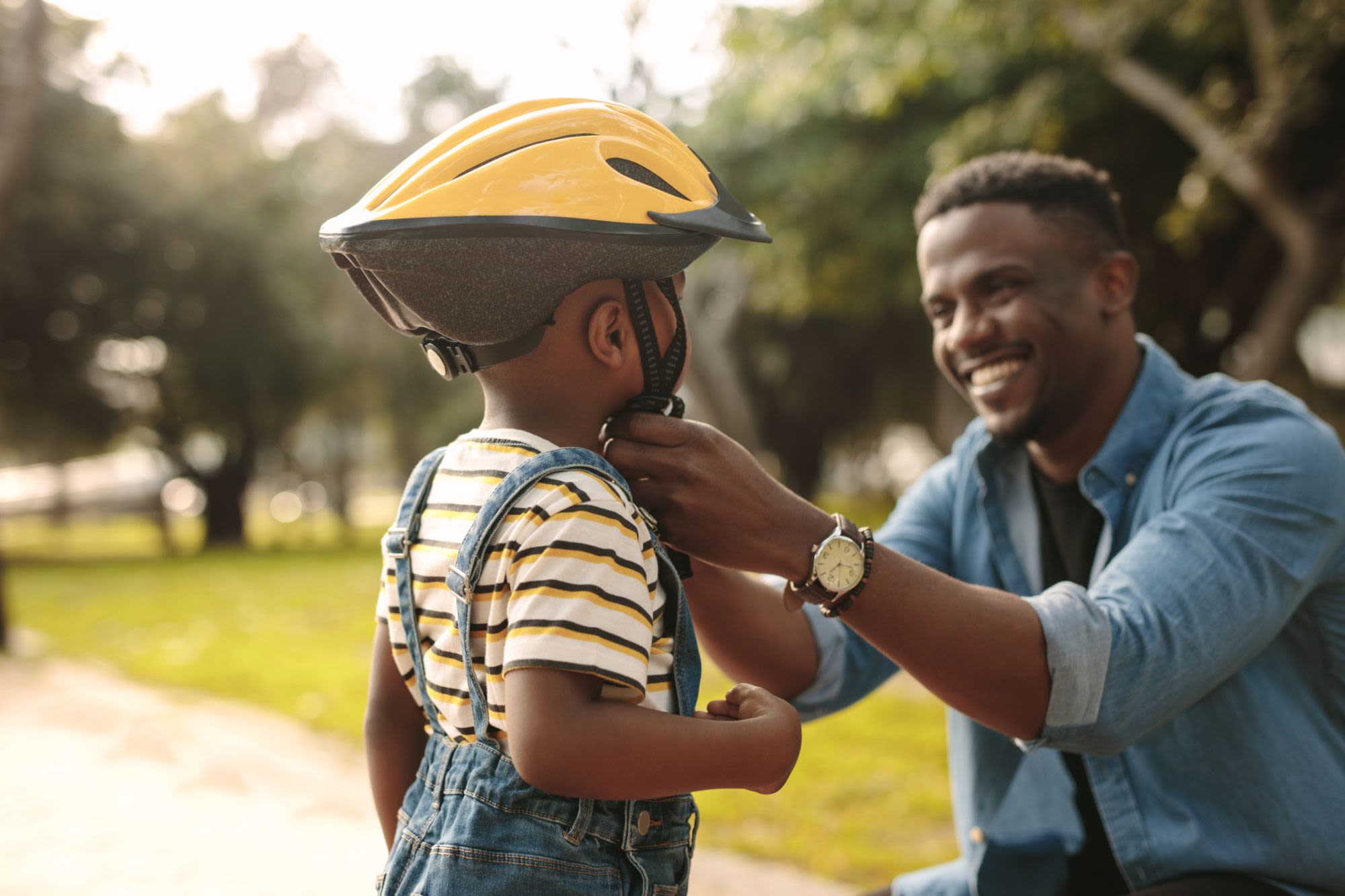 Father putting a bike helmet on his child near The Iris in San Antonio, Texas