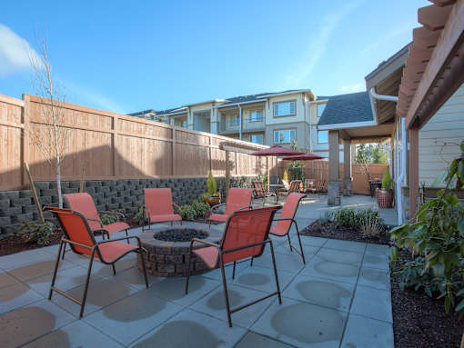 A patio with a table and chairs is surrounded by a wooden fence. at Mill Creek Meadows Apartments, Mill Creek, WA