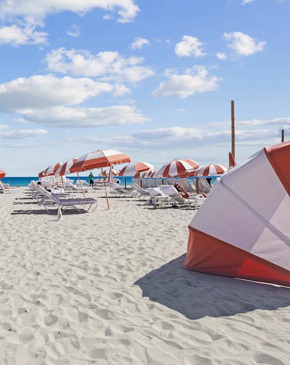 A beach scene with umbrellas and chairs.