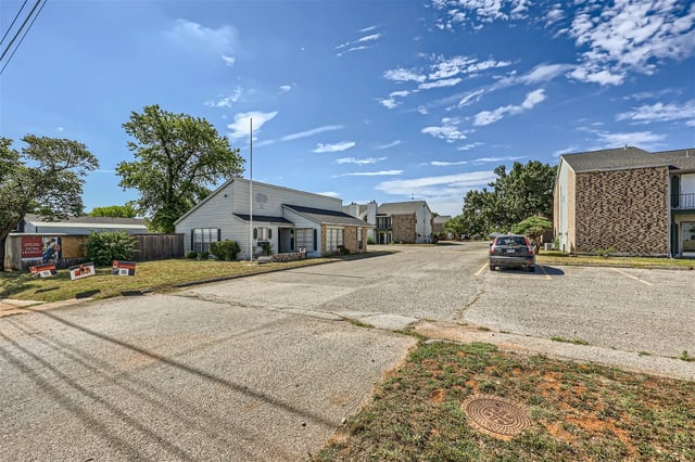 View of the apartment complex's exterior with a parking lot and leasing signs.