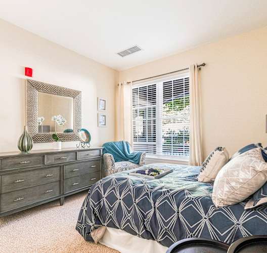 A bedroom with a bed, dresser, and mirror.