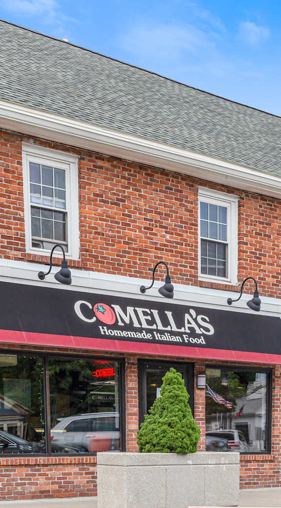 A brick building with a black awning that says "COMELLA'S Homemade Italian Food".