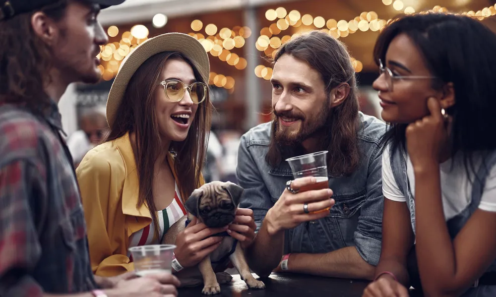 four people with drinks and dog outside