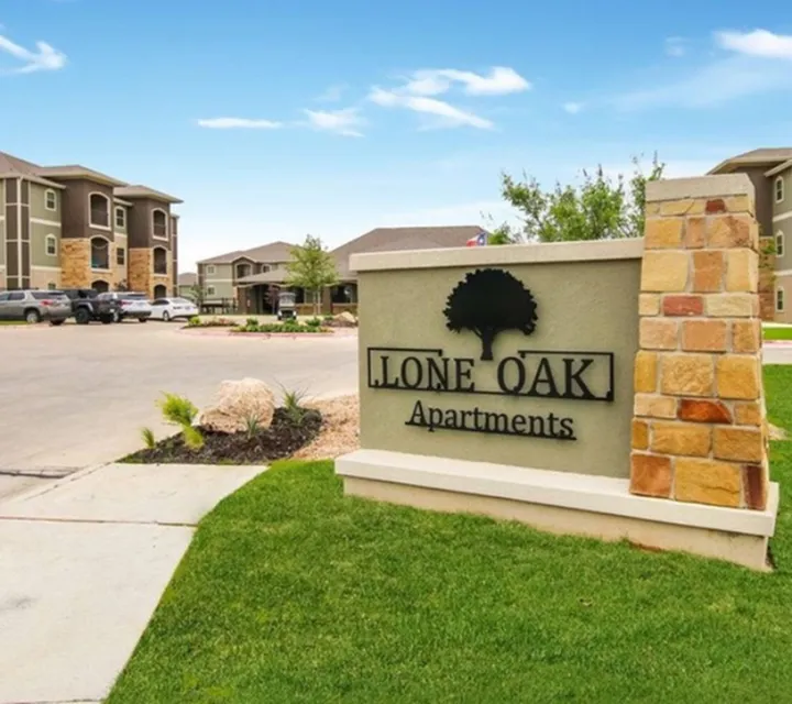 Inviting exterior of Lone Oak Apartments with elegant stone accents and lush green landscaping.