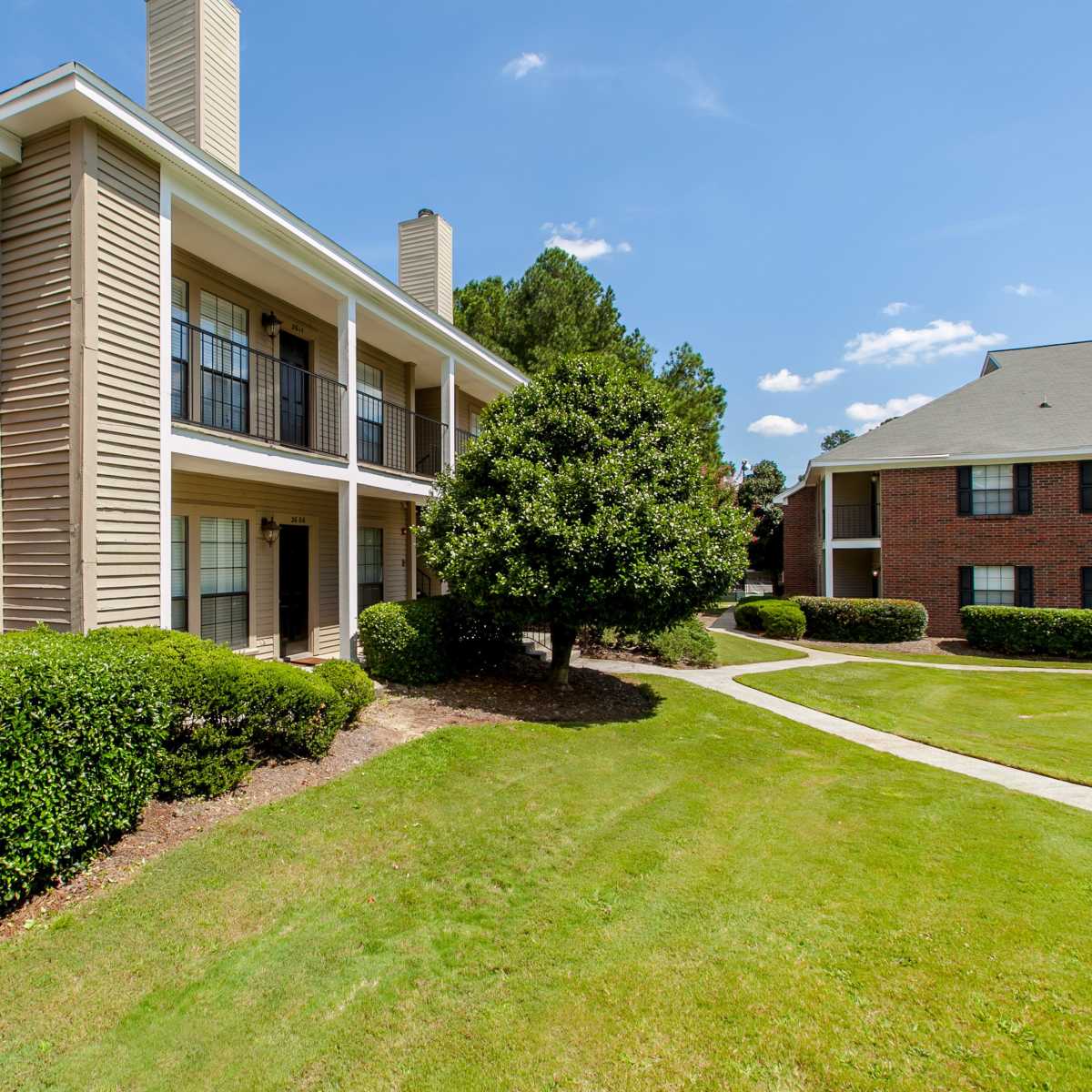 Building exterior showing lush landscaping and private balconies and patios at Marks Church Commons in Augusta, Georgia