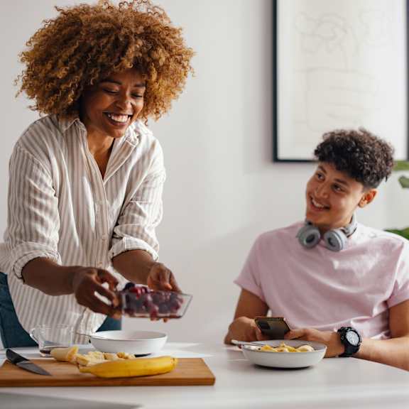A woman with curly hair is serving food to a man who is wearing headphones and a pink shirt.