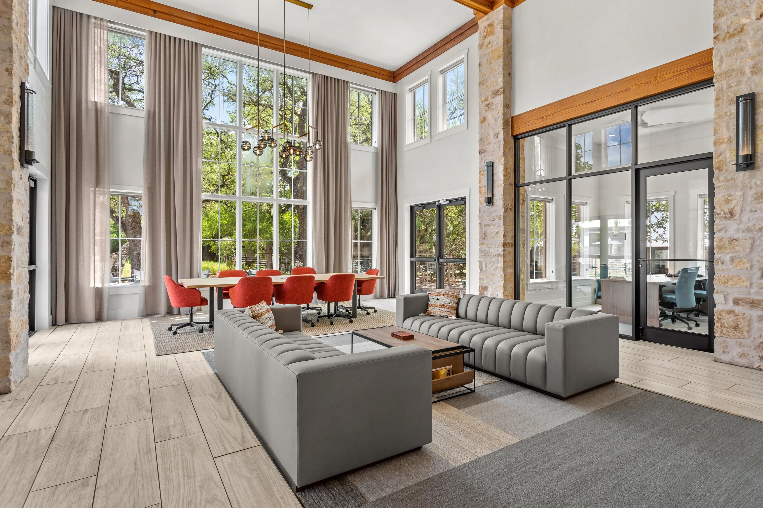 Stylish community lounge with large windows, comfortable seating, and a dining area.