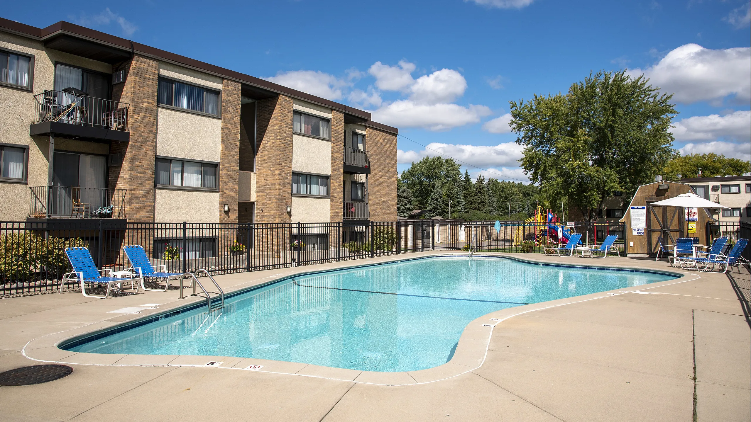 ReNew Meadow Lake's inviting apartment complex featuring a sparkling swimming pool and sun loungers, perfect for relaxation and leisure.