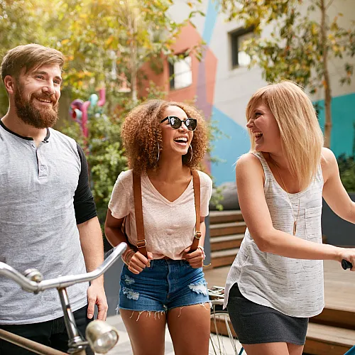 Vibrant group of friends enjoying a sunny day, highlighted by colorful street art and bicycles.