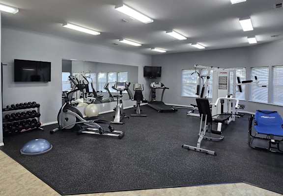 A spacious gym with a variety of equipment including treadmills, stationary bikes, and weight machines.
