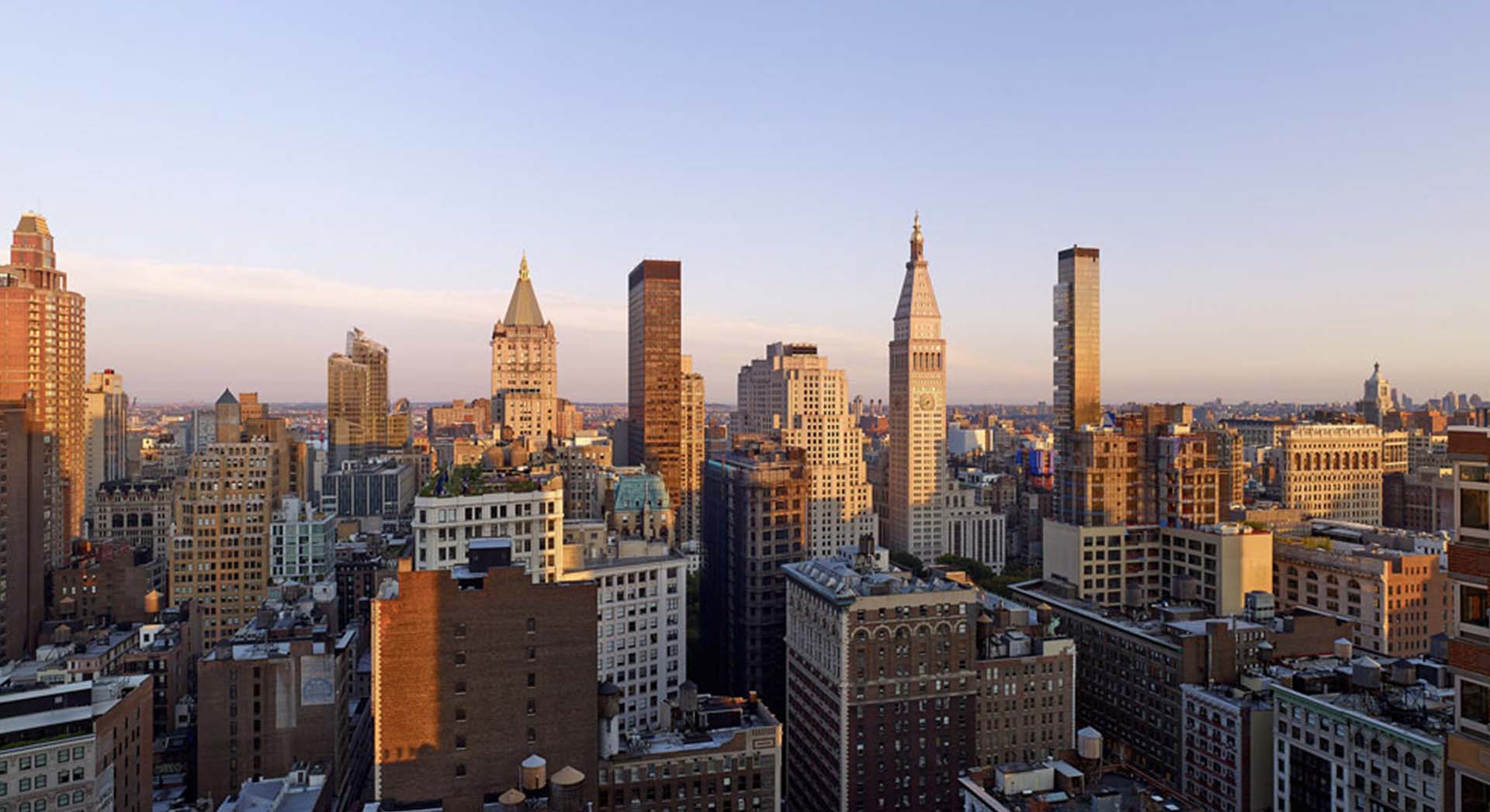 rooftop view of manhattan looking downtown during the day with clear skies and the tops of buildings