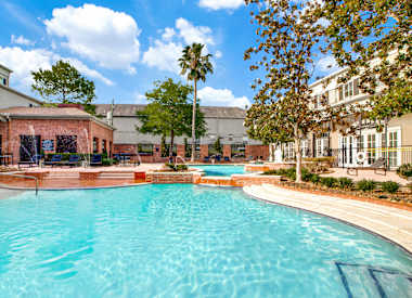 A large swimming pool in the middle of a courtyard surrounded by trees and buildings.