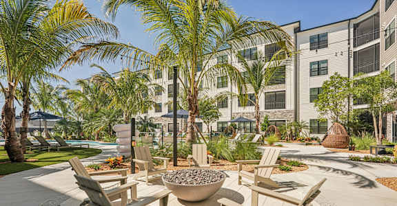 A patio with chairs and a fire pit in front of a building at The Stadler Luxury Apartments, Bradenton, Florida