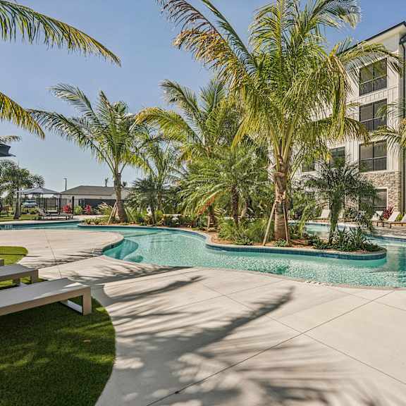 A pool surrounded by palm trees at The Stadler Luxury Apartments, Florida 34210