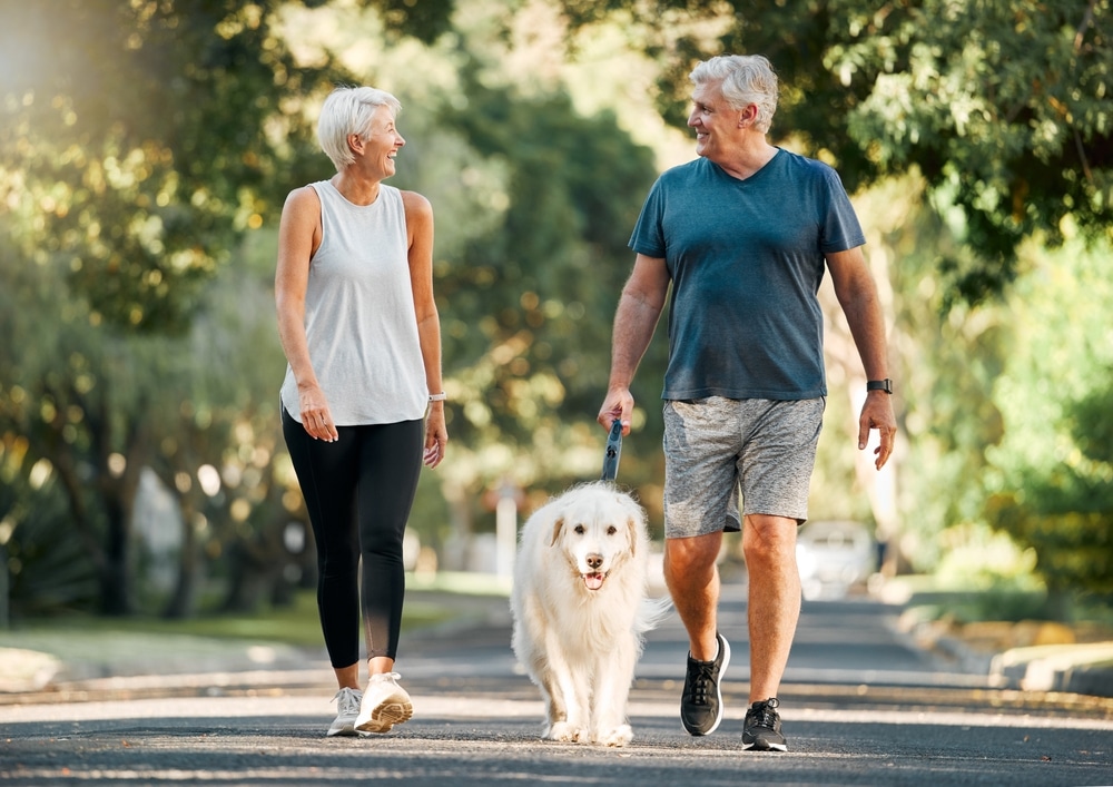 55+ woman and men walking with a dog around their neighborhood
