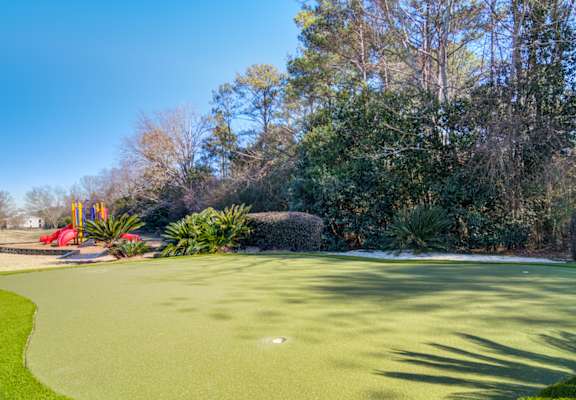 a putting green with trees in the background