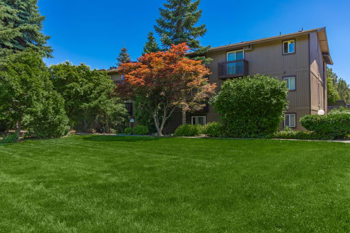 an apartment building with green grass and trees in front of it at Lincoln Village Apartments, Washington