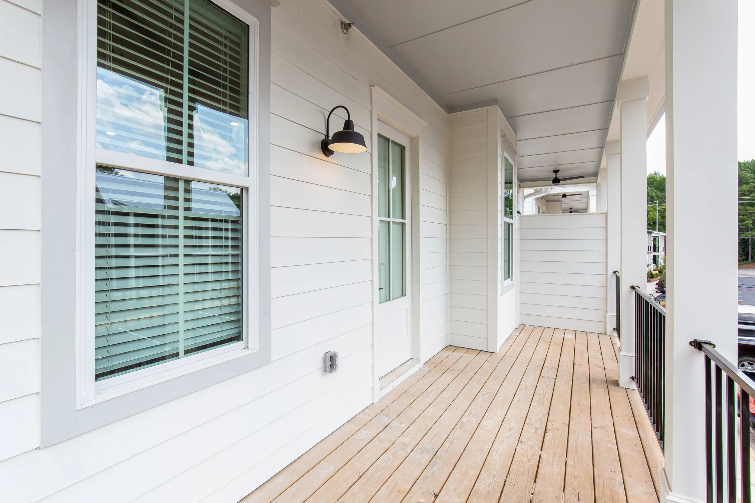 A side-angle view down the length of a spacious, private front porch at The One Clemson, perfect for relaxing and enjoying the neighborhood.