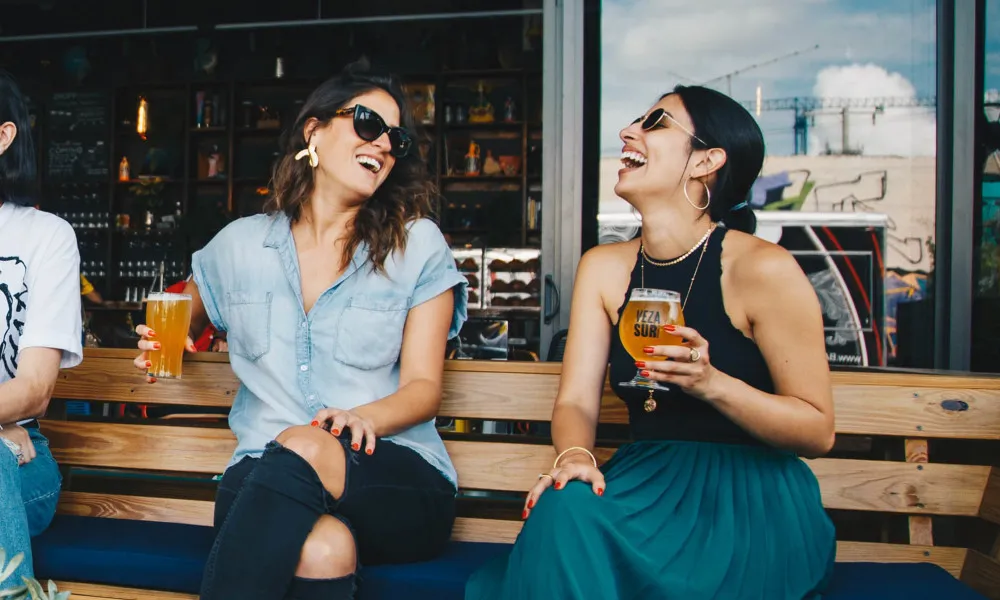two women with beers in hand outside restaurant
